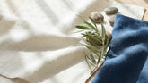 Tissu en lin japonais asa blanc et bleu indigo plie sur un bois clair en lumiere d ete