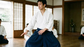Aikidoka en hakama bleu et gi blanc en posture de garde dans un dojo traditionnel