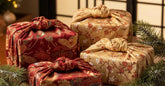 Cadeaux de Noel emballes dans du furoshiki rouge et or a motifs japonais avec branches de pin