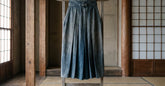 Hakama ancien plissé présenté sur un support en bois dans une salle traditionnelle