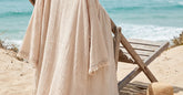 Kimono de plage en voile clair posé sur un transat en bois face à la mer
