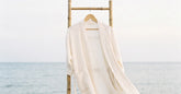 Kimono de plage en coton blanc suspendu au bord de la mer sous une lumière douce