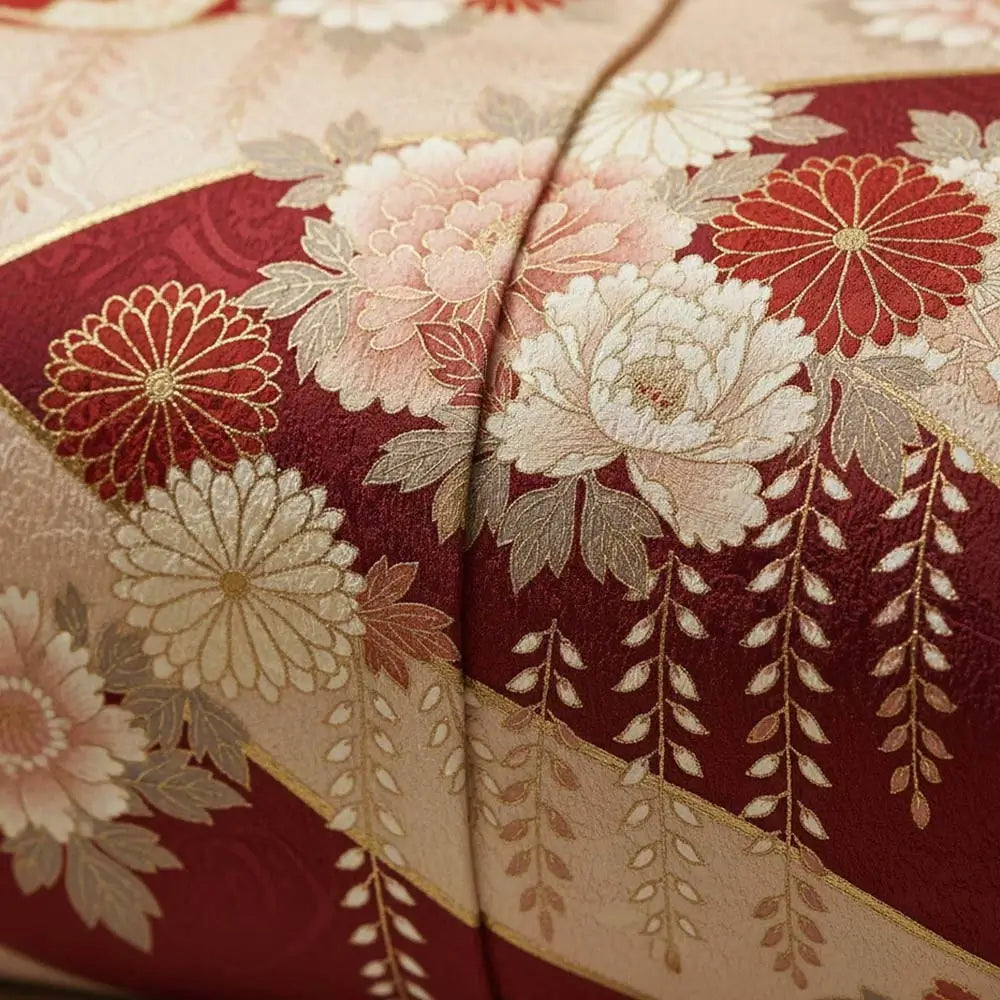 DĂ©tail dâun tissu de kimono japonais en soie, ornĂ© de motifs floraux rouges, dorĂ©s et ivoire reprĂ©sentant des pivoines et des chrysanthĂšmes, symbole dâĂ©lĂ©gance et de tradition.