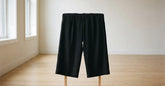 Pantalon large japonais homme noir présenté sur un support en bois dans une pièce claire