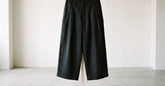 Pantalon japonais homme noir à jambe large présenté dans un intérieur minimaliste