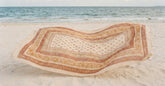 Paréo de plage en voile de coton étalé sur le sable face à la mer