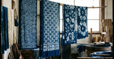 Tissu shibori indigo aux motifs noués séchant sur une corde en bois clair