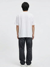 Vue de dos du pantalon baggy homme Kuro Classic noir, coupe large et décontractée en denim, tombé droit jusqu’aux chevilles, porté avec t-shirt blanc ample et sneakers blanches sur fond blanc.
