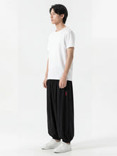 Pantalon japonais homme Kurozen noir coupe ample vu de profil, style hakama moderne, porté avec t-shirt blanc et sneakers sur fond blanc