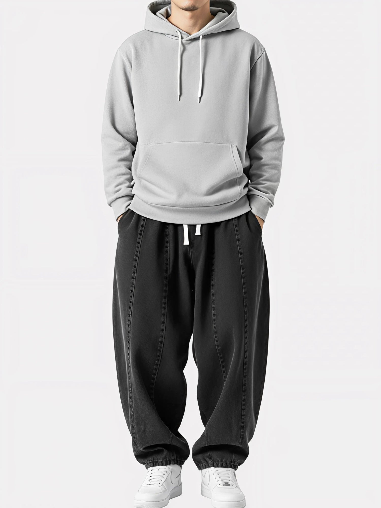 Homme debout portant le Jeans Sora noir, pantalon kimono japonais ample avec cordon blanc, coupe fluide et allure urbaine épurée.