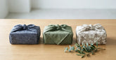 Cadeaux japonais emballés dans du tissu posés sur une table en bois clair