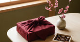 Coffret cadeau japonais emballé dans un furoshiki rouge avec chocolats et fleurs