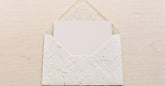 Carte cadeau glissée dans une enveloppe en papier washi sur une table claire