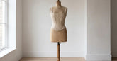 Corset en coton beige présenté sur un buste de couturière dans une pièce claire