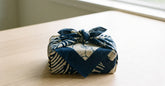 Cadeau emballé dans un furoshiki en tissu japonais noué posé sur une table claire