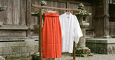 Hakama femme rouge vermillon et haut blanc présentés devant un sanctuaire japonais