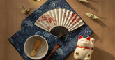 Objets cadeaux japonais : eventail, furoshiki, set de matcha, maneki neko et grues en origami sur une table