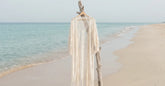 Kimono de plage blanc en dentelle suspendu au bord de la mer sous une lumière douce