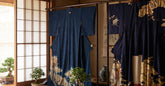 Plusieurs kimonos traditionnels japonais en soie indigo et motifs dores exposes dans un interieur en bois