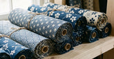Rouleaux de tissus japonais à motifs traditionnels alignés sur une étagère claire
