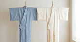 Yukata en coton bleu et kimono en soie suspendus côte à côte sur des supports en bois