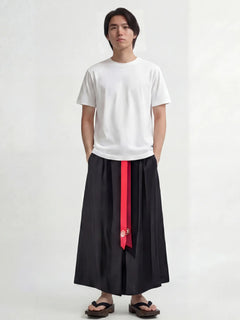 Pantalon hakama homme Kōsei noir, pantalon japonais traditionnel à plis larges avec ceinture rouge, porté avec t-shirt blanc et sandales, style minimaliste et élégant.