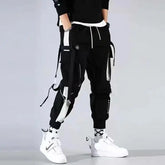 Homme portant le Pantalon Cargo Japonais Urban Street Tactical noir, coupe streetwear avec multi-poches et sangles décoratives.