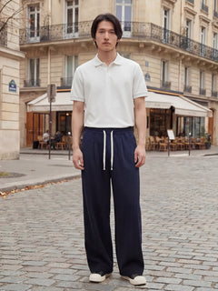 Pantalon japonais homme Akeno porté avec un polo blanc, coupe ample plissée bleu marine, taille élastique avec cordon, style japonais urbain élégant en rue parisienne