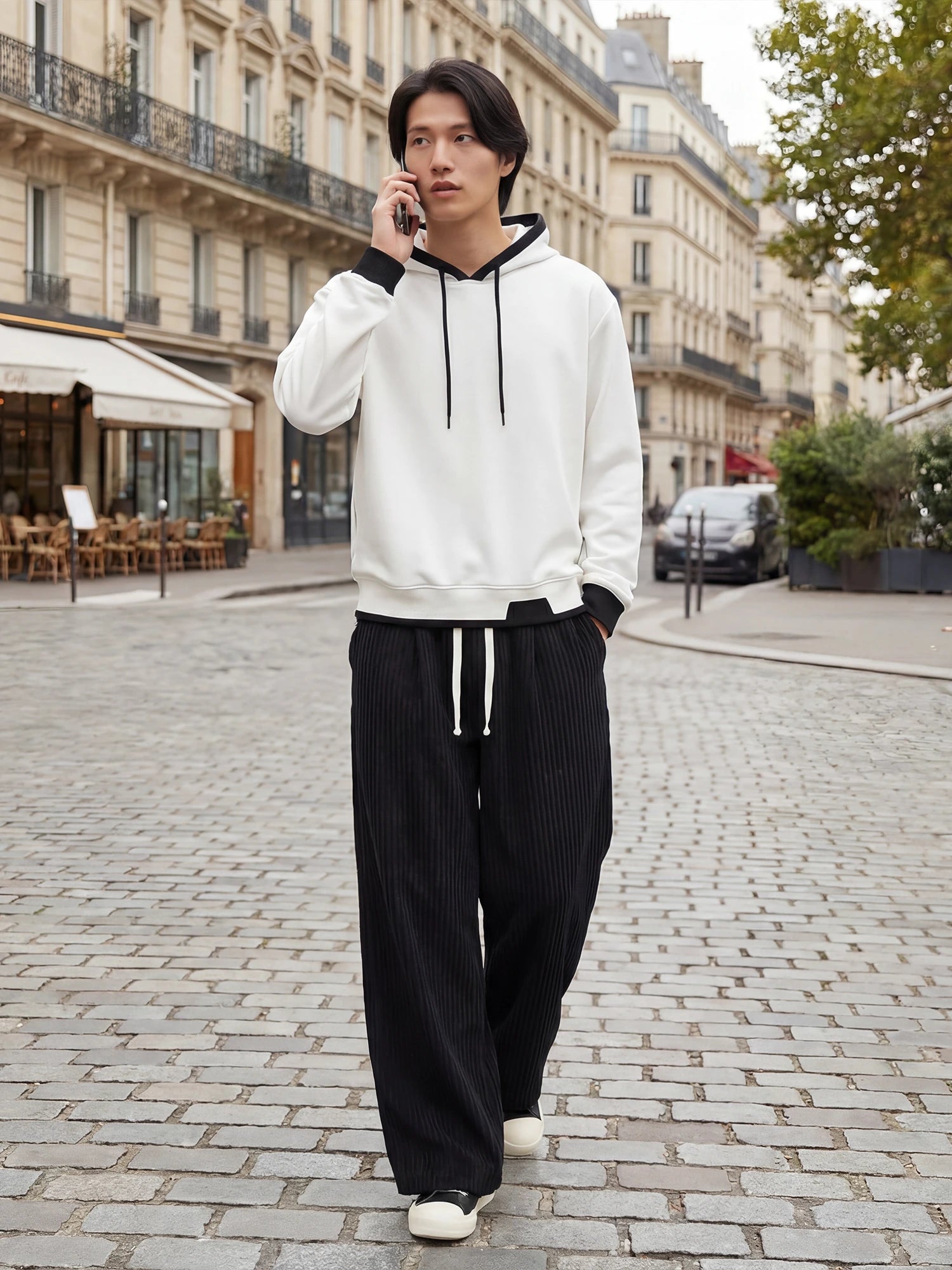 Pantalon japonais homme Akeno porté en ville, coupe ample plissée noire, taille élastique avec cordon, style japonais urbain moderne dans une rue parisienne