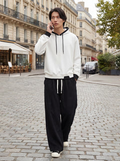 Pantalon japonais homme Akeno porté en ville, coupe ample plissée noire, taille élastique avec cordon, style japonais urbain moderne dans une rue parisienne