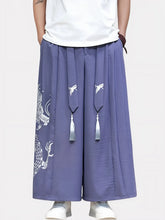 Homme debout portant un pantalon kimono violet orné d’un dragon brodé, coupe large et taille élastique inspirée de la mode japonaise.