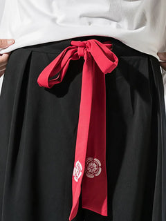 Détail du pantalon hakama homme Kōsei noir avec ceinture japonaise rouge nouée, finition soignée et symbole floral inspiré du Japon.