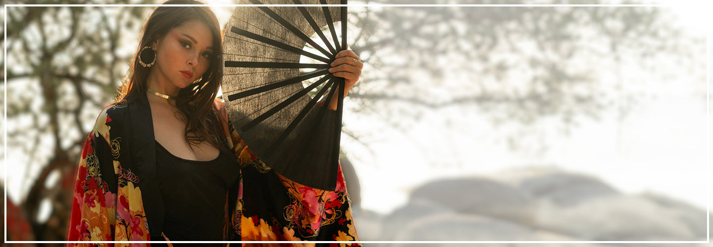 Femme élégante portant un kimono japonais floral rouge et noir, tenant un éventail noir, ambiance asiatique raffinée