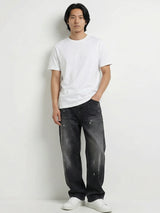 Pantalon baggy homme Kuro Classic noir, coupe large et décontractée, denim effet légèrement usé, porté avec t-shirt blanc et sneakers blanches sur fond blanc, style urbain minimaliste.