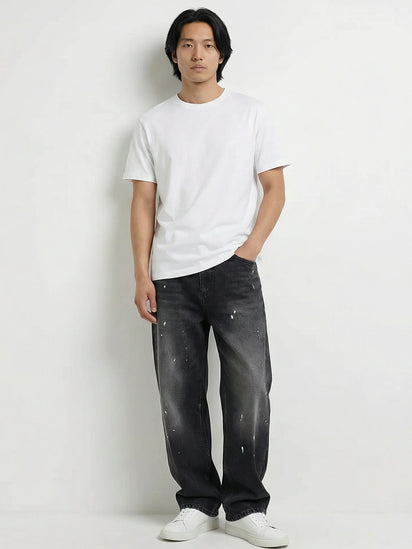 Pantalon baggy homme Kuro Classic noir, coupe large et décontractée, denim effet légèrement usé, porté avec t-shirt blanc et sneakers blanches sur fond blanc, style urbain minimaliste.