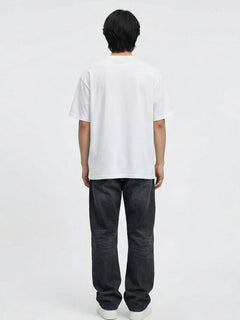 Vue de dos du pantalon baggy homme Kuro Classic noir, coupe large et décontractée en denim, tombé droit jusqu’aux chevilles, porté avec t-shirt blanc ample et sneakers blanches sur fond blanc.