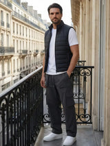 Pantalon casual japonais cargo pour homme porté debout sur un balcon parisien, coloris gris foncé, coupe ample et structurée, poches cargo latérales, style minimaliste inspiré du Japon, élégance urbaine contemporaine.