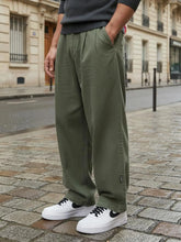 Pantalon casual japonais vert kaki pour homme, coupe large fluide au style minimaliste, porté en milieu urbain