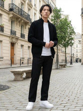 Pantalon droit japonais noir pour homme, coupe épurée et moderne, porté avec t-shirt blanc et cardigan noir dans une rue parisienne