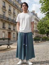 Pantalon hakama homme Kōsei bleu porté en ville, pantalon japonais large et fluide avec ceinture contrastée, style minimaliste et élégant.