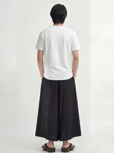 Pantalon hakama homme Kōsei noir vu de dos, pantalon japonais large à plis profonds, coupe fluide et élégante, porté avec t-shirt blanc.