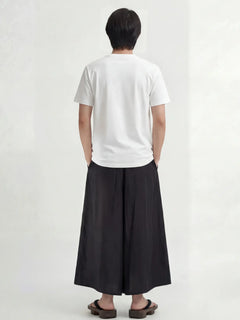 Pantalon hakama homme Kōsei noir vu de dos, pantalon japonais large à plis profonds, coupe fluide et élégante, porté avec t-shirt blanc.