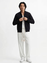 Pantalon homme japonais Natsu blanc, coupe fluide et confortable avec taille élastique et cordon, porté avec débardeur blanc, veste noire zippée et sneakers blanches sur fond blanc, style minimaliste et moderne.