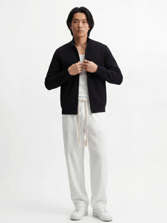 Pantalon homme japonais Natsu blanc, coupe fluide et confortable avec taille élastique et cordon, porté avec débardeur blanc, veste noire zippée et sneakers blanches sur fond blanc, style minimaliste et moderne.