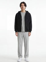 Pantalon japonais droit gris clair pour homme, silhouette fluide et minimaliste, porté de face avec hoodie noir et sneakers blanches sur fond studio