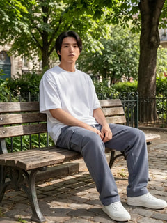 Pantalon japonais homme Hikari gris porté en extérieur, assis dans un parc urbain au style parisien