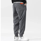 Pantalon japonais homme Kenji gris vu de dos, coupe ample en velours côtelé avec étiquette orange, style japonais moderne et décontracté.