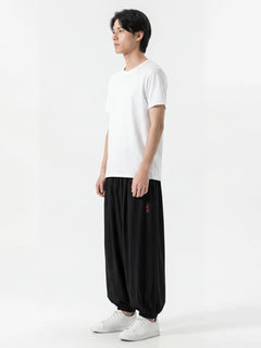 Pantalon japonais homme Kurozen noir coupe ample vu de profil, style hakama moderne, porté avec t-shirt blanc et sneakers sur fond blanc
