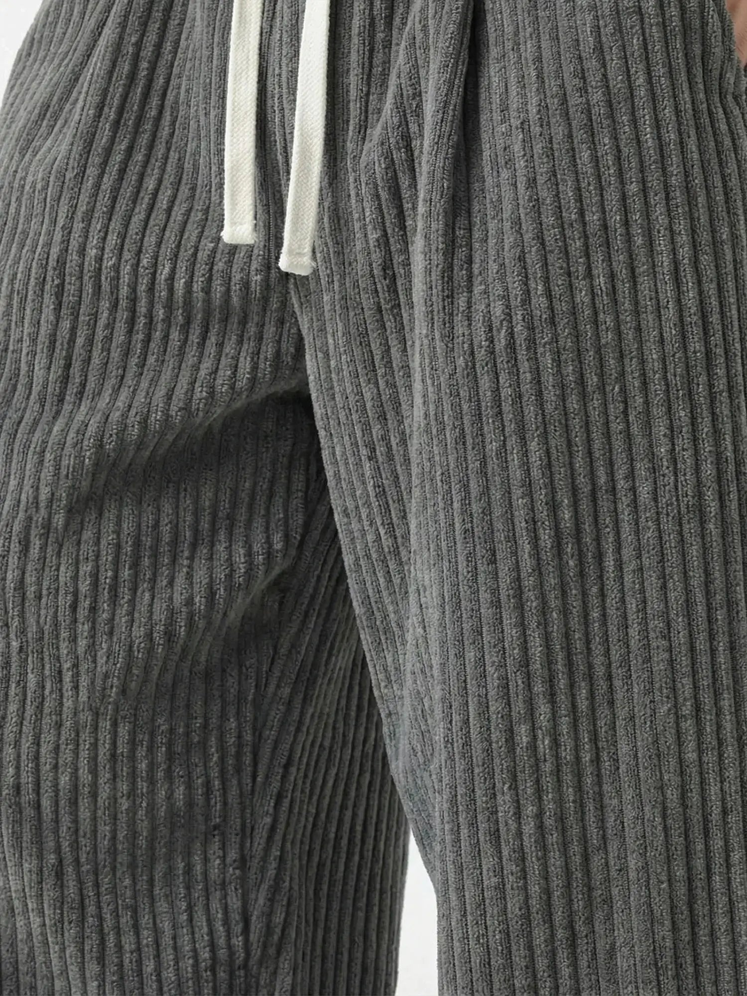Zoom sur le tissu du pantalon japonais homme Akeno, matière plissée verticale gris anthracite, texture douce et fluide, cordon de serrage visible