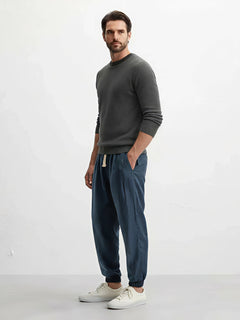 Pantalon style japonais pour homme, coupe ample et fluide, taille élastique avec cordon, coloris bleu profond, porté avec sneakers blanches sur fond clair.